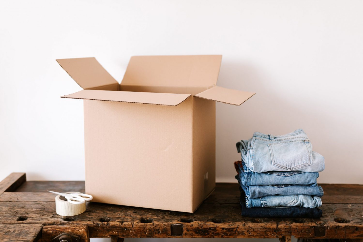 stack-of-jeans-near-carton-box-and-tape-4498141